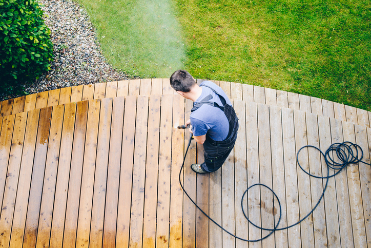 cleaning terrace with a power washer – high water pressure cleaner on wooden terrace surface